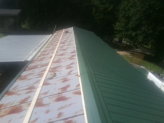 Old rusted panels beside newly installed green metal roofing — Wind Damage Roof Repair by Roofing Brothers in La Follette