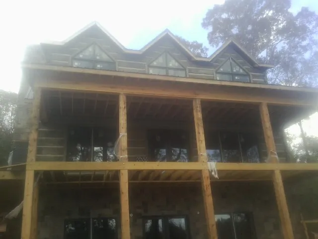 Dormers and porch framing on a large log home under construction — Roof Coating work by our crew in La Follette