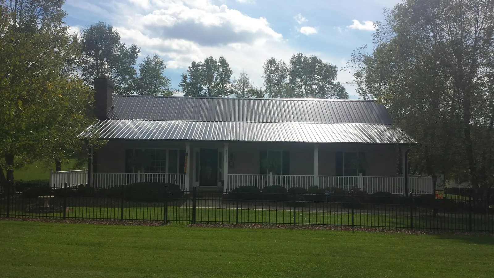 Gray metal roof on a brick ranch with a full width front porch — Gutter Guard Installation work by our crew in La Follette