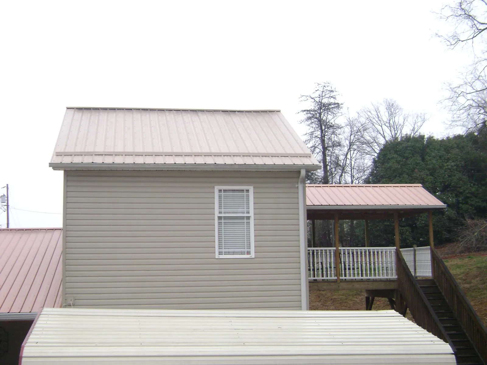 Tan metal roofs on a two story addition and attached porch, from a Roof Replacement job in La Follette