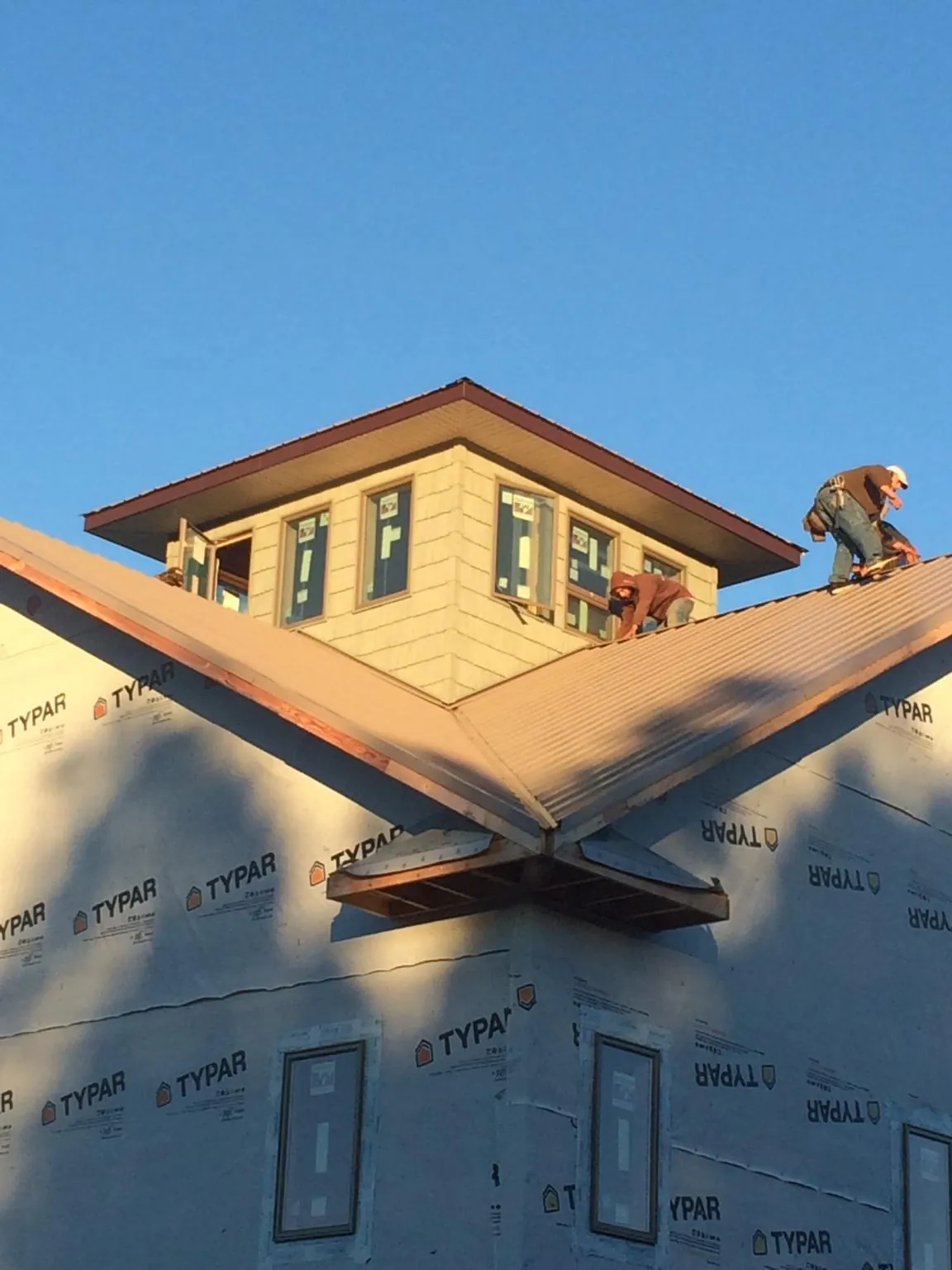 Roofers working around a rooftop cupola on a new metal roof at sunset — Roof Waterproofing in La Follette by Roofing Brothers